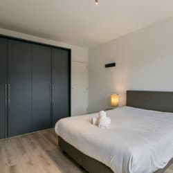 een slaapkamer appartement met diensten schone handdoeken op een tweepersoonsbed met kledingkast