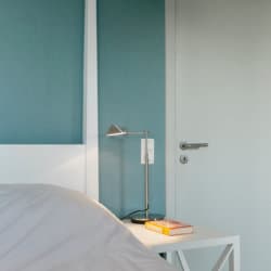 tweepersoonsbed met bijzettafel en lamp in gemeubileerd appartement met diensten