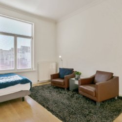 spacious bedroom with double bed and two sofa chairs in brussels city