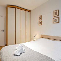 tweepersoonsbed in grote slaapkamer met ingebouwde kasten bij bois de la cambre