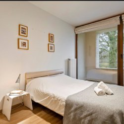 tweepersoonsbed in grote slaapkamer met ingebouwde kasten bij bois de la cambre